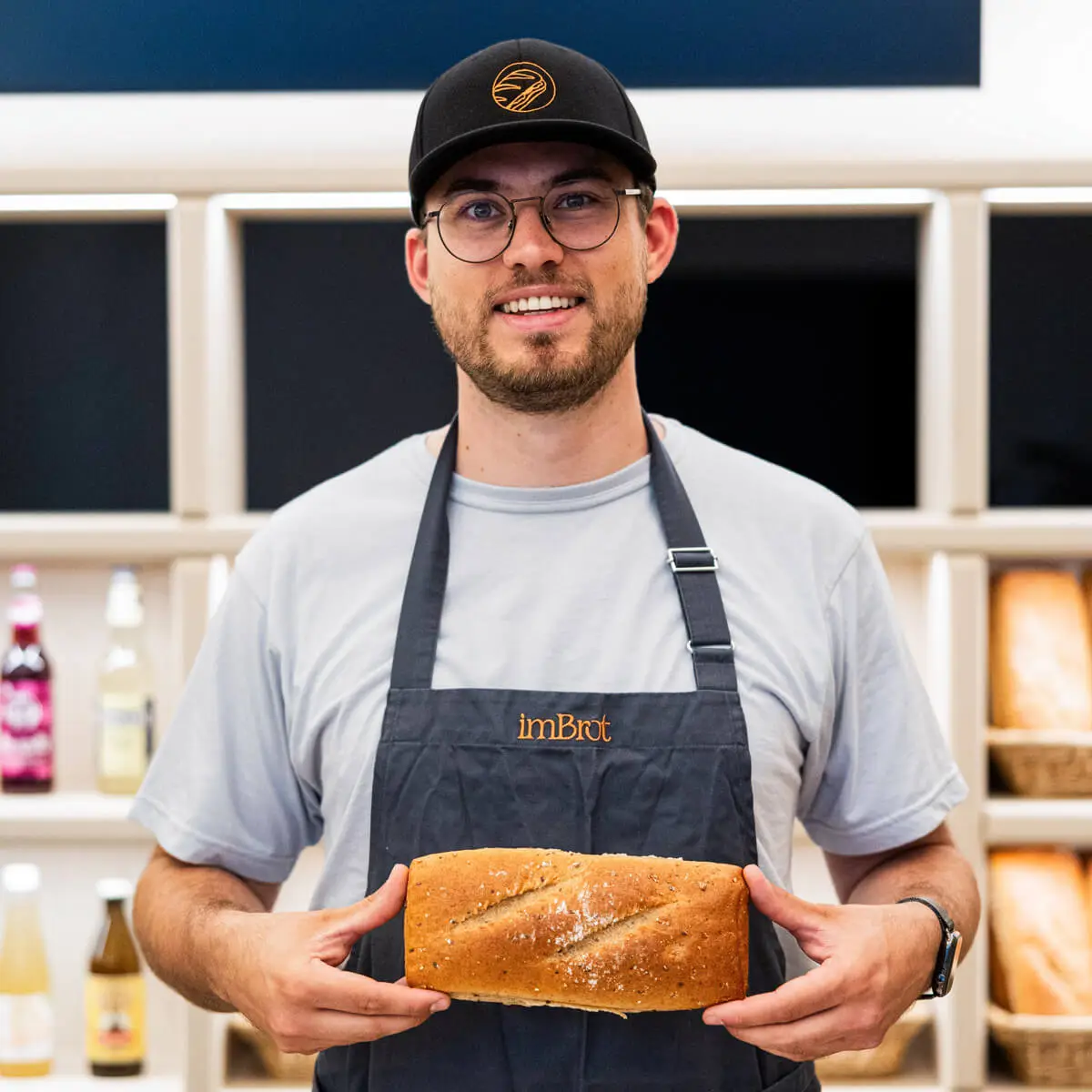 Ein Mitarbeiter hält ein frisches Brot in der Hand. Ein Mitarbeiter hält ein frisches Brot in der Hand.